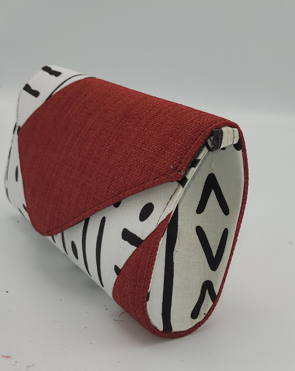 “Side view of a red, white, and black cotton canvas shoulder clutch from Senegal.”
