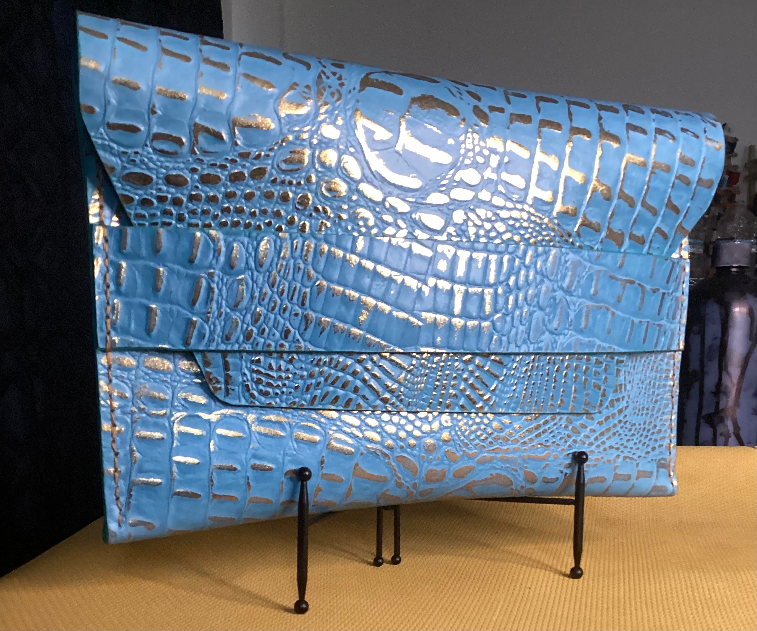 “Élan No. 04 Turquoise Guilt croco-embossed envelope clutch, front view.”
