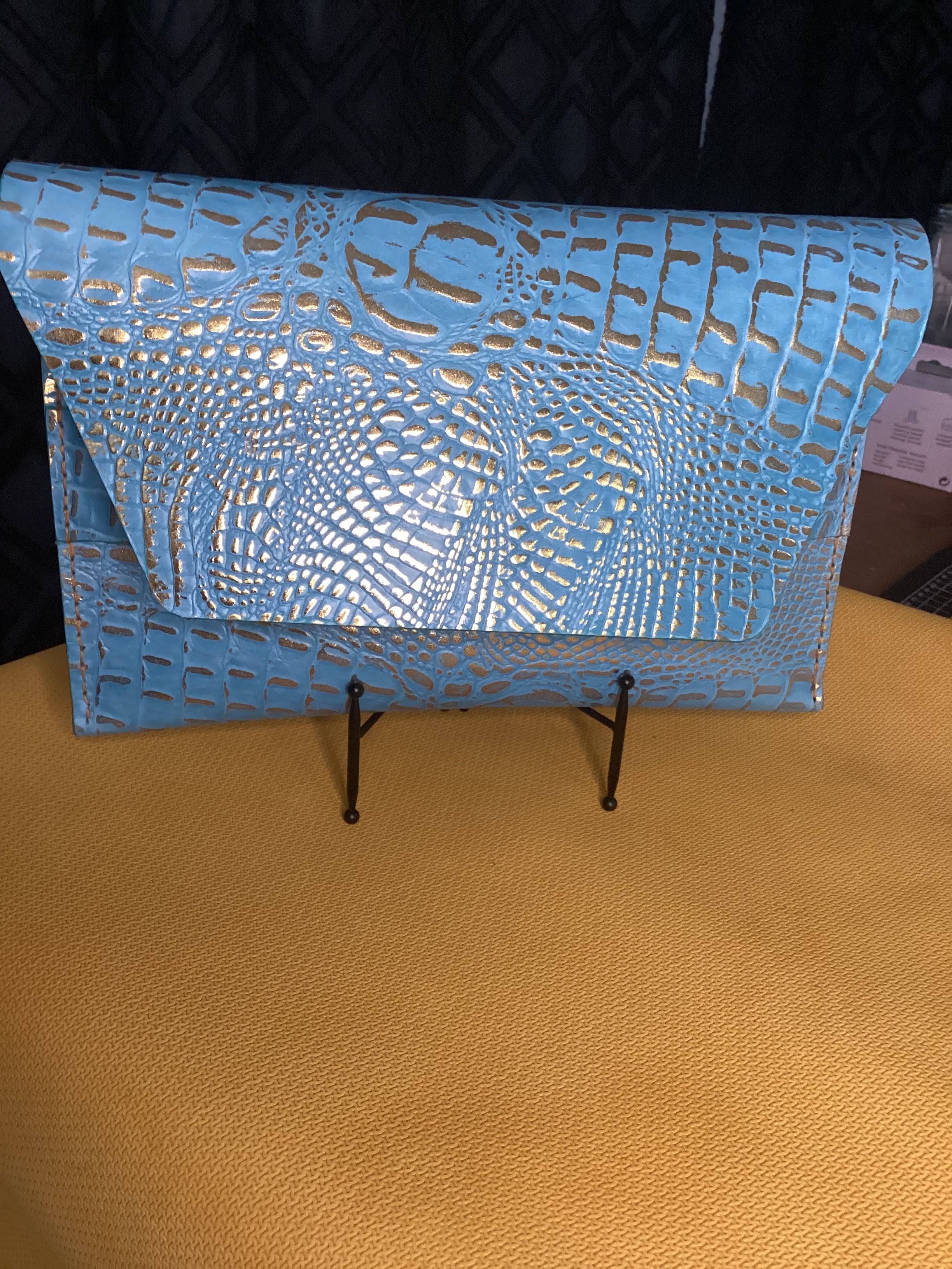“Élan No. 04 clutch showing the turquoise croco-embossed texture.”